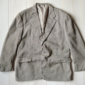 May include: A brown tweed blazer with a single-breasted closure and two flap pockets.
