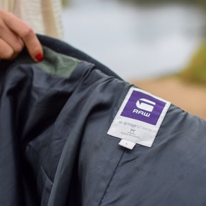 May include: A black jacket with a purple G-Star RAW label. The label says "G-Star RAW" and "Made in China".