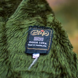 May include: A green fuzzy jacket with a black label that reads "Blijuch Industria Konfekcjie Banja Luka Made in Yugoslavia".