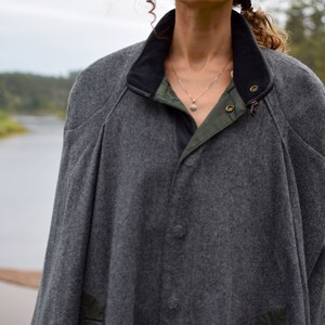 May include: A gray wool jacket with a black collar and a green lining. The jacket has a button closure and a zipper.