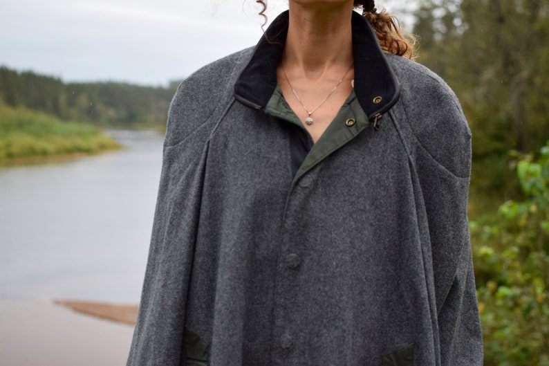 May include: A gray wool jacket with a black collar and a green lining. The jacket has a button closure and a zipper.