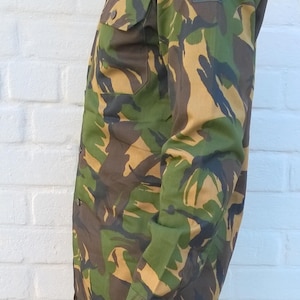May include: A camouflage long-sleeved shirt with a Dutch flag patch on the sleeve.