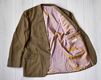 May include: A brown and tan plaid blazer with a pink lining. The blazer has a single button closure and two pockets on the front.