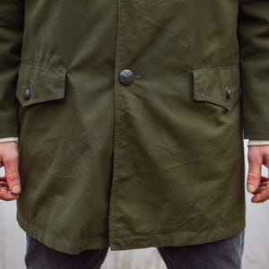 May include: A dark green long-sleeved jacket with two large pockets and a button closure.