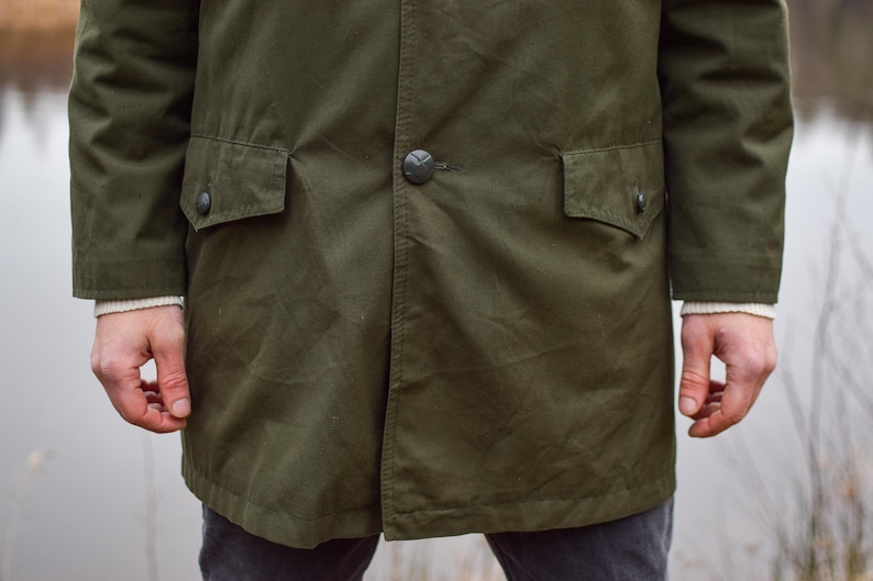 May include: A dark green long-sleeved jacket with two large pockets and a button closure.