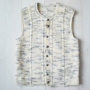 May include: A white knitted vest with a cable knit pattern and button closures. The vest has a subtle gray fleck throughout the fabric.