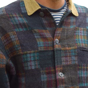 Op de afbeelding: Een overhemd met lange mouwen en knopen met een donker ruitpatroon in marineblauw, talinggroen en bordeauxrood. Het overhemd heeft een beige corduroy kraag en wordt gedragen over een wit en marineblauw horizontaal gestreept shirt eronder.
