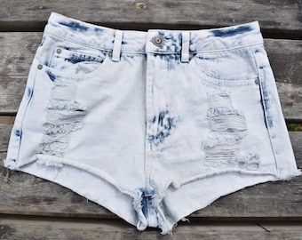May include: Light blue denim shorts with distressed details and a faded wash. The shorts have a high waist and a relaxed fit.