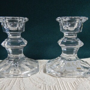 May include: A pair of clear glass candle holders with a faceted design. The candle holders are made by Mikasa.