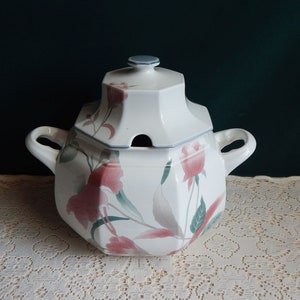 May include: White ceramic soup tureen with a lid and two handles. The tureen is decorated with a floral pattern in shades of pink, green, and gray.
