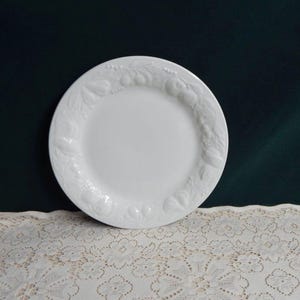 May include: White ceramic plate with a raised design of fruit and leaves around the rim.