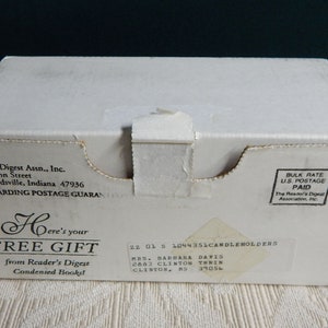 May include: A white cardboard box with black text that reads "Here's your FREE GIFT from Reader's Digest Condensed Books". The box also has a label with the text "22 01 5 1044351CANDLEHOLDERS MRS. BARBARA DAVIS 2883 CLINTON THRIEN CLISTOR, KS 39056".