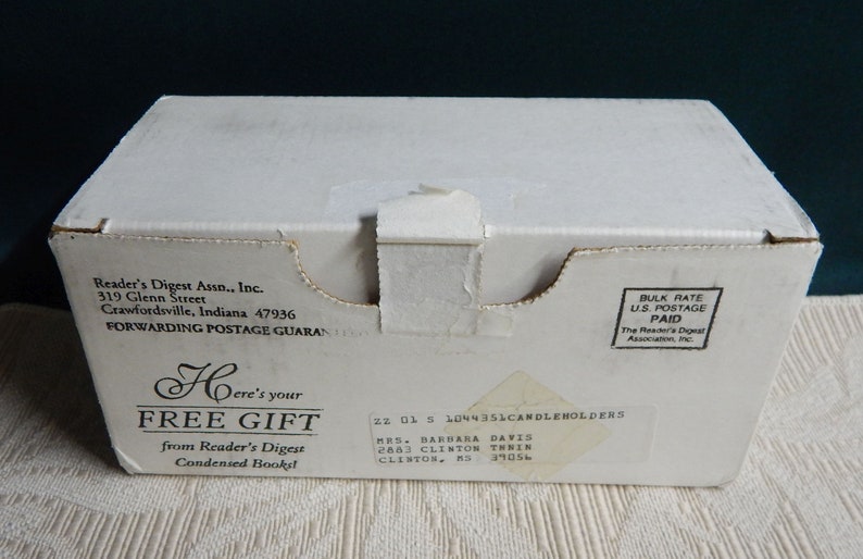 May include: A white cardboard box with black text that reads "Here's your FREE GIFT from Reader's Digest Condensed Books". The box also has a label with the text "22 01 5 1044351CANDLEHOLDERS MRS. BARBARA DAVIS 2883 CLINTON THRIEN CLISTOR, KS 39056".