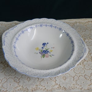 May include: A white oval serving bowl with a blue and white floral design. The bowl has a scalloped edge and a blue polka dot pattern.