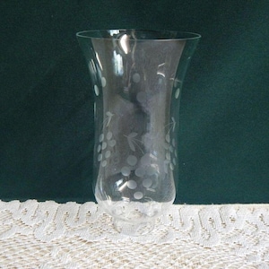May include: A clear glass hurricane lamp shade with a flared top and a narrow base. The exterior surface features a delicate, etched design of grape clusters and leaves, providing a frosted appearance against the transparent glass body.