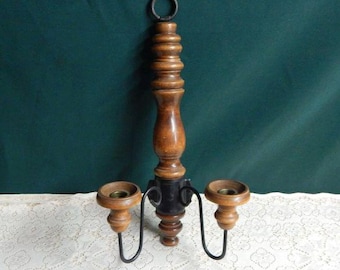 May include: A wooden wall-mounted candle holder with three arms and a black metal finish. The holder has a dark wood finish and is decorated with a simple design.