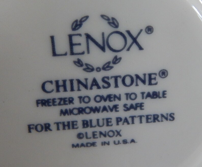 May include: Close-up of a white ceramic plate with blue text that reads "LENOX&reg; CHINASTONE&reg; FREEZER TO OVEN TO TABLE MICROWAVE SAFE FOR THE BLUE PATTERNS OLENOX MADE IN U.S.A."