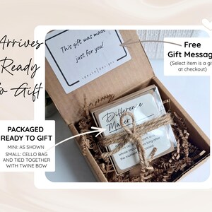 May include: A brown cardboard gift box filled with brown paper crinkle filler. Inside, a square item is wrapped in a clear plastic sleeve and tied with a brown twine bow. A white sticker inside the lid reads This gift was made just for you.