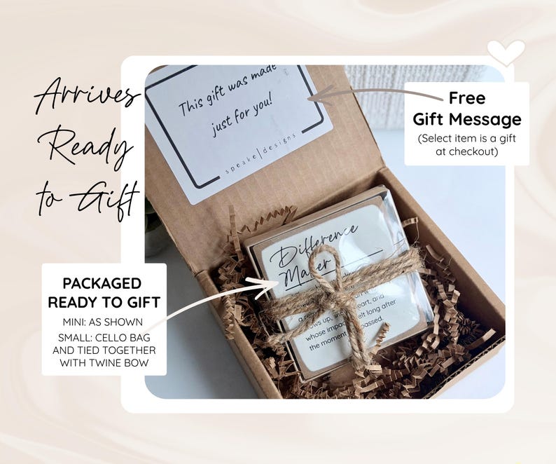 May include: A brown cardboard gift box filled with brown paper crinkle filler. Inside, a square item is wrapped in a clear plastic sleeve and tied with a brown twine bow. A white sticker inside the lid reads This gift was made just for you.