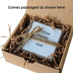May include: A brown cardboard box with a white card inside. The card has the text "DESIGN from this HERE" written on it. The box is filled with brown packing paper.
