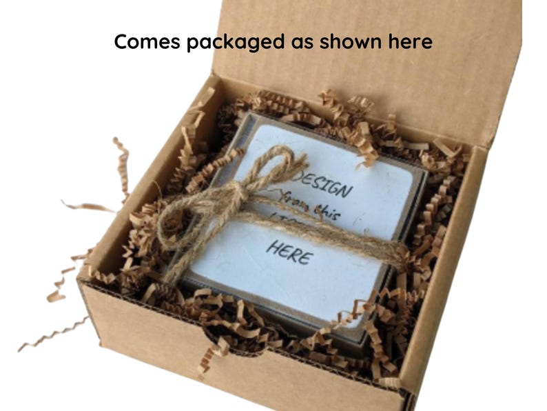May include: A brown cardboard box with a white card inside. The card has the text "DESIGN from this HERE" written on it. The box is filled with brown packing paper.