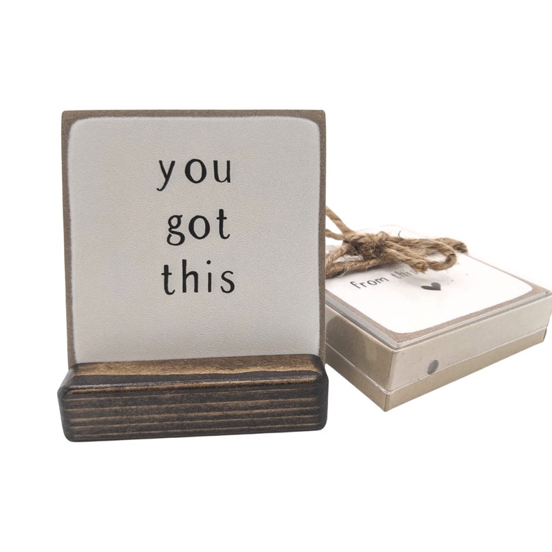 Może przedstawiać: Mały drewniany znak z tekstem "you got this" czarnymi literami na białym tle. Znak stoi na małym drewnianym stojaku i ma brązową wstążkę ze sznurka z małą etykietą w kształcie serca, na kt&oacute;rej napisano "from the heart".