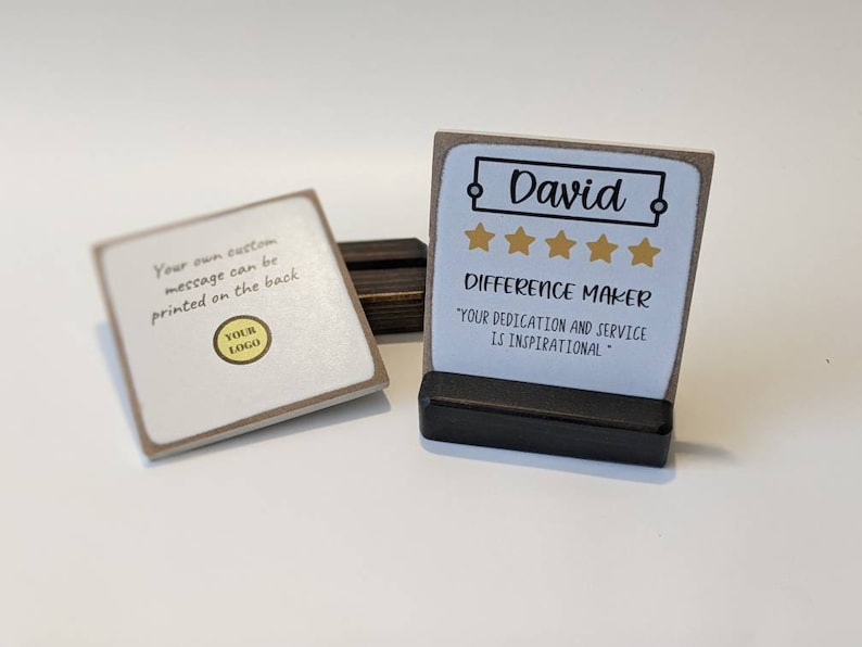 May include: A small, brown wooden plaque with a white background and gold stars. The plaque has the name "David" and the text "Difference Maker" with the quote "Your dedication and service is inspirational".
