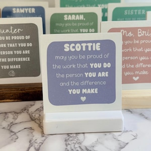 May include: A square light purple wooden sign with a white base, featuring the text: SCOTTIE, may you be proud of the work that you do, the person you are, and the difference you make, with a small white heart icon below the text.