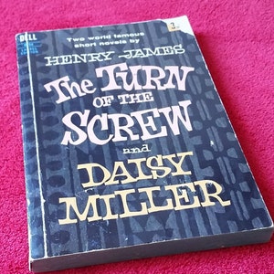 Peut inclure: Un livre broché noir et blanc avec le titre "The Turn of the Screw and Daisy Miller" de Henry James. La couverture du livre présente un motif noir et blanc.