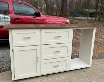 May include: White cabinet with a wood countertop, four drawers, a cabinet door, and an open shelf. The cabinet is standing on a concrete surface.