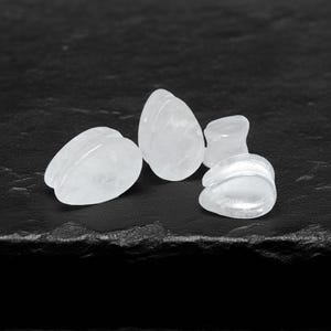 May include: Four clear, teardrop-shaped ear plugs are displayed on a dark surface. The plugs are made of a translucent material, with a smooth, polished appearance. The plugs vary slightly in size and shape, with a rounded, flared design.