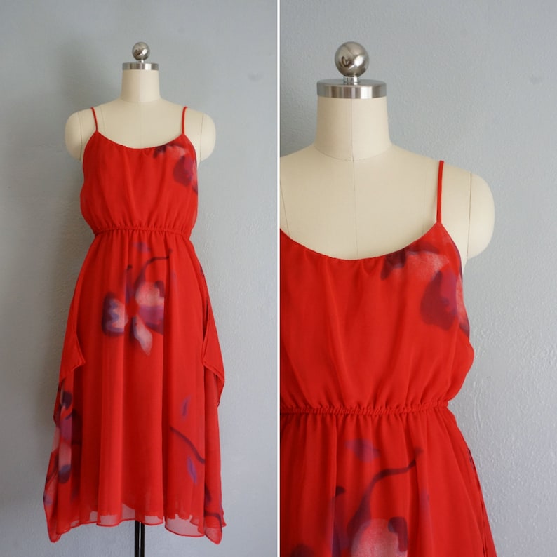 May include: A red sleeveless dress with a floral print. The dress has a fitted bodice and a flowing skirt.