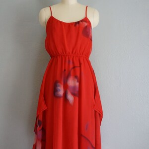 May include: A red sleeveless dress with a floral print. The dress has a gathered waist and a flowing skirt.