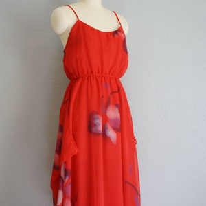 May include: A red sleeveless dress with a floral print. The dress has a fitted bodice and a flowing skirt.