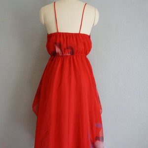 May include: A red sleeveless dress with a floral print. The dress has a gathered waist and a tiered skirt.