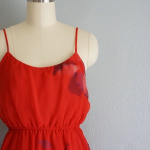 May include: A red sleeveless dress with a floral print. The dress has a fitted bodice and a flowing skirt.