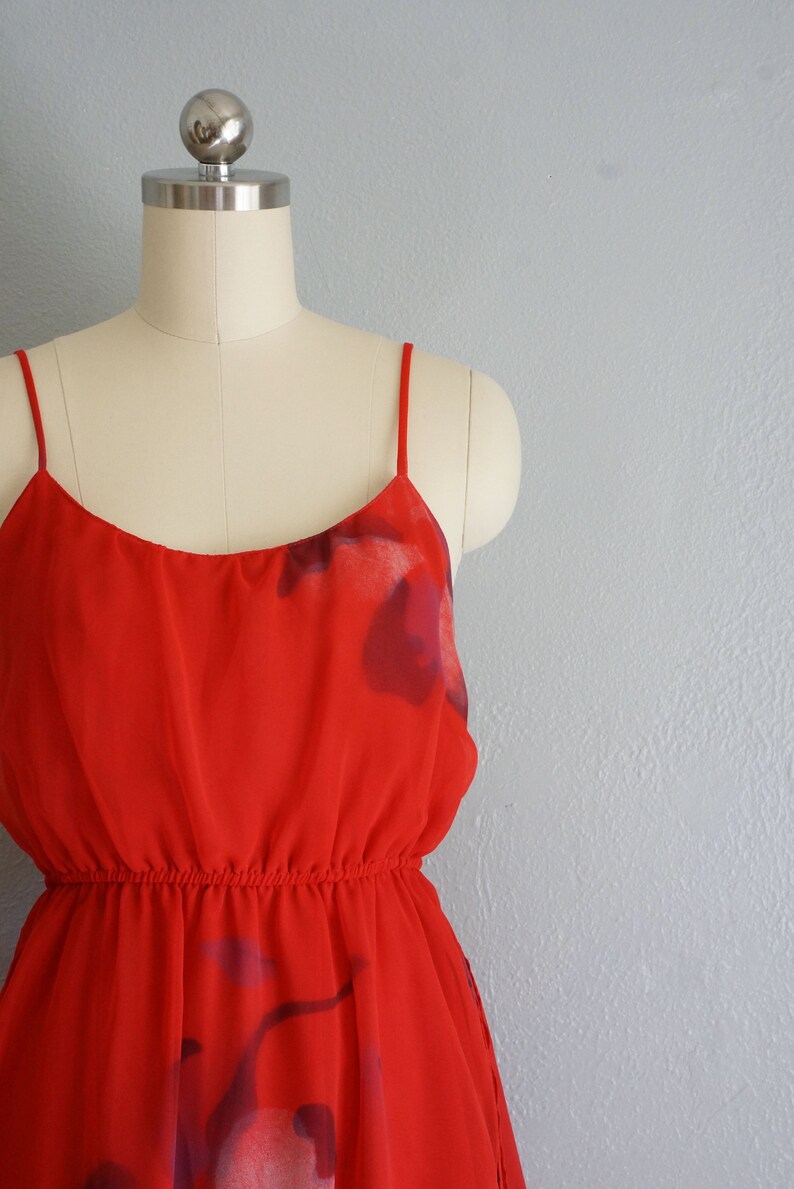 May include: A red sleeveless dress with a floral print. The dress has a fitted bodice and a flowing skirt.