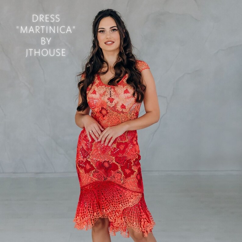 May include: A woman wearing a red crochet dress with a floral pattern. The dress has a fitted bodice and a flowing skirt. The dress is called "Martinica" by Jthouse.