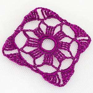 以下が含まれることがあります： 正方形のマゼンタ色のかぎ針編みドイリー。中央に円形の穴があり、放射状の線と透かし模様があります。縁はスカラップで、白い背景に配置されています。
