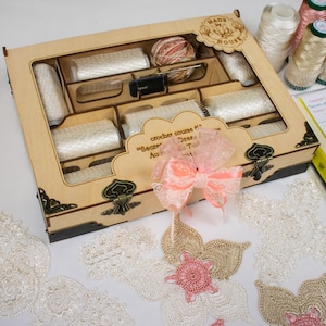 May include: A wooden box with a clear lid filled with spools of white thread and a crochet hook. The box has a label that says "crochet course #1 "Secrets of Dreams" Author: Olga Turova". There is a pink and white bow on the box.