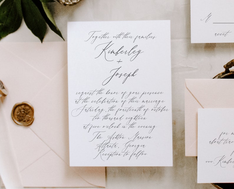 May include: A white wedding invitation with black calligraphy text. The invitation reads "Together with their families, Kimberley + Joseph request the honor of your presence at the celebration of their marriage Saturday, the fourteenth of October, two thousand eighteen at five o'clock in the evening. The Ashton Mansion, Atlanta, Georgia. Reception to follow."