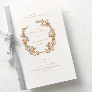 May include: A wedding invitation with a gold floral wreath and the names "Eirini Giannakopoulou" and "Konstantinos Natsis". The invitation is for June 12th, 2026 at 6 PM at St. George Greek Orthodox Cathedral in Chicago, IL.
