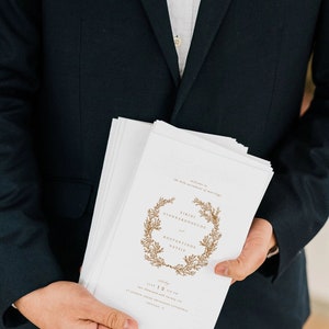 May include: A white wedding program with a gold wreath design and the text "Welcome to the holy sacrament of marriage" and "Eirini Giannakopoulou and Konstantinos Natsi"s. The program also includes the date "June 12, 2017" and the time "Six thirty PM".