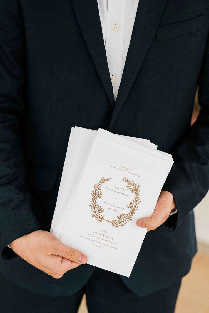 May include: A white wedding program with a gold wreath design and the text "Welcome to the holy sacrament of marriage" and "Eirini Giannakopoulou and Konstantinos Natsi"s. The program also includes the date "June 12, 2017" and the time "Six thirty PM".