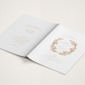 May include: A white wedding program with gold text and a floral wreath design. The program includes the names "Eirini Giannakopoulou" and "Agustinos Natzis" and the date "July 1st, 2023".
