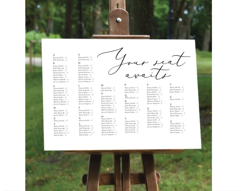 May include: A white seating chart with black text lists guest names and table numbers. The chart is on an easel and says "Your seat awaits".