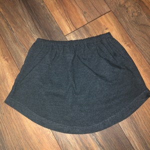 May include: A dark gray, short, stretchy skirt with a wide elastic waistband.