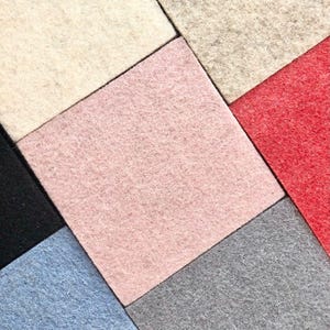 Puede incluir: Vista cenital de cuadrados de fieltro de colores dispuestos en un patr&oacute;n geom&eacute;trico. Los colores incluyen crema, rosa, rojo, negro, azul y gris. El fieltro tiene un aspecto suave y texturizado, creando una disposici&oacute;n visualmente atractiva.