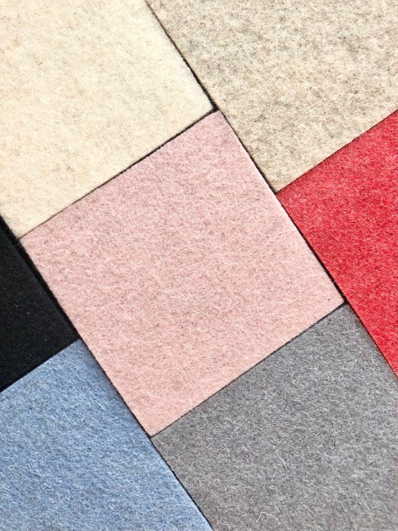 Puede incluir: Vista cenital de cuadrados de fieltro de colores dispuestos en un patr&oacute;n geom&eacute;trico. Los colores incluyen crema, rosa, rojo, negro, azul y gris. El fieltro tiene un aspecto suave y texturizado, creando una disposici&oacute;n visualmente atractiva.
