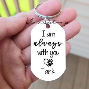 May include: White oval keychain with the text "I am always with you" and a paw print inside a heart. The name "Tank" is printed below the heart.